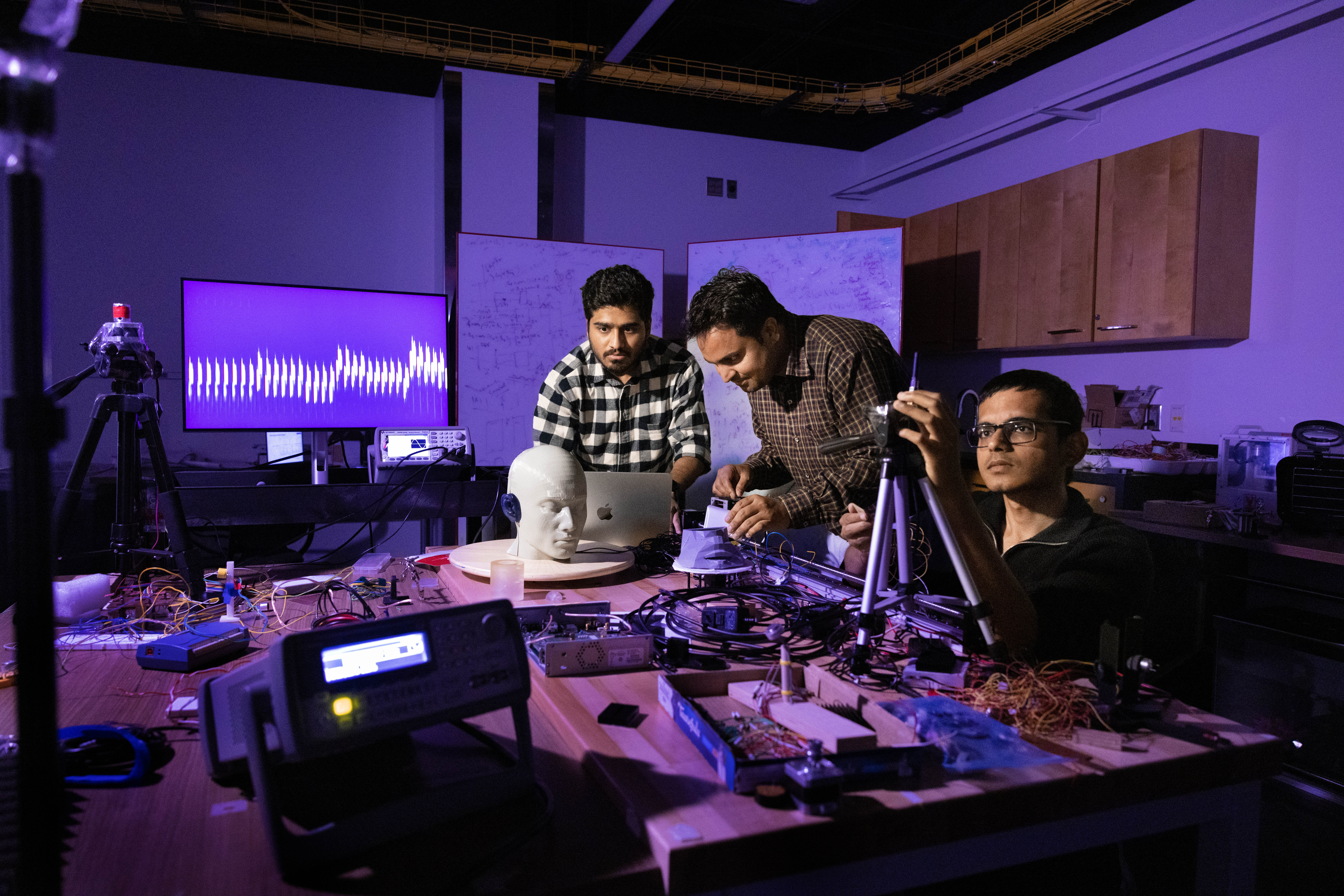 Nirupam Roy and two students work at a workbench in the AI radio frequency lab